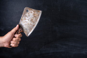 Old kitchen cleaver in the chef's hand on a dark background