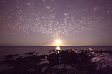 Moonlight and starry sky illuminating the ocean on the Big Island, Kohala Coast