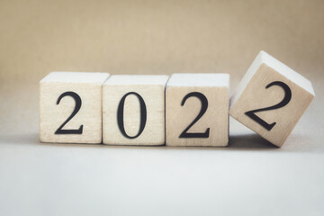 The year 2022 written on wooden cubes, finger flipping year to year, New year concept background, starting new natural modern colored design stylish