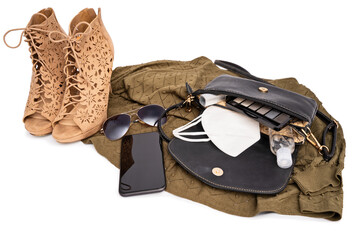 Modern stylish female outfit for the pandemic with high heels, green dress, hat, glasses, mobile phone, purse with makeup, hand sanitizer and face mask, isolated on white background. The COVID-19 new 