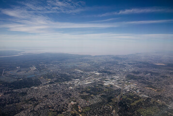 Obraz premium Flying over Buenos Aires. Cityscape. Aerial view of the city from very high. The town buildings, houses, streets and vast extension of land under a blue sky. Beautiful urban texture and pattern.