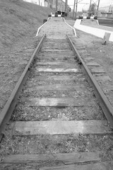 Obraz premium The dead end of the railway ends with a mound and signs prohibiting traffic. Black and white image.