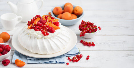 Homemade Pavlova cake with fresh raspberries, red currants and apricots. Copy space.  Selective focus 