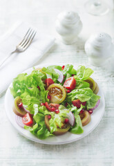 Salad with red and yellow Tomatoes and Pomegranate Seeds on bright wooden Background. Close up. 