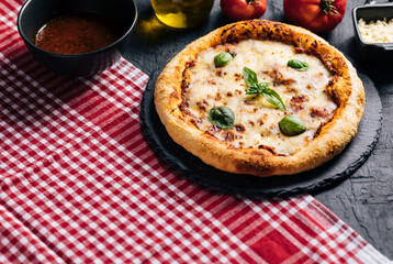 Traditional Margherita Pizza with basil, tomato, olive oil, mozzarella on a rustic background