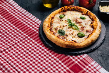 Traditional Margherita Pizza with basil, tomato, olive oil, mozzarella on a rustic background