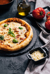 Traditional Margherita Pizza with basil, tomato, olive oil, mozzarella on a rustic background