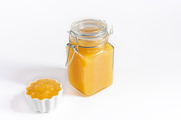 Yellow jam on a white background. Fruit homemade confiture in a jar and a bowl close up. Copy space.