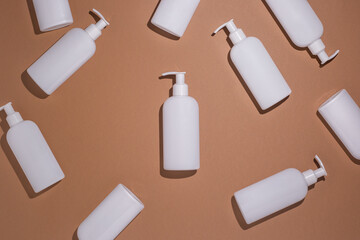 White bottles with a dispenser lie on a brown cardboard background. Top view, flat lay