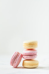 Stack of yellow and pink macaroons with shallow depth of field on the white background.