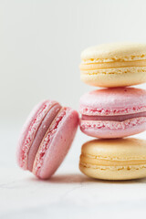 Stack of yellow and pink macaroons with shallow depth of field on the white background.