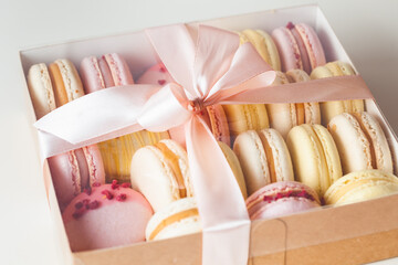 Flat lay of yellow and pink macaroons on the white background. Macro shot of French sweet dessert...