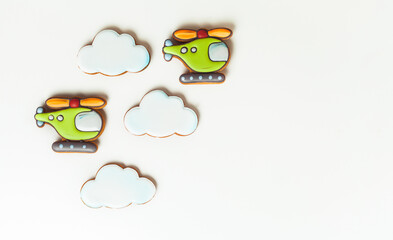 Gingerbread cookies in the shape of military helicopters flying in the clouds. Army or Men's day. Flat lay on white.