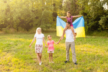 Fototapeta premium Happy family s with flag of Ukraine in field.