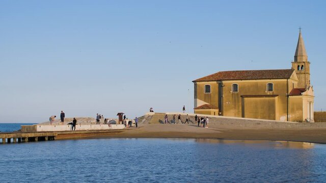 A small church on the beach in the Italian town Caorle in Veneto, Italy. The coastal Catholic chapel during sunset is a famous landmark and tourist attraction during the summer holidays. 4K.