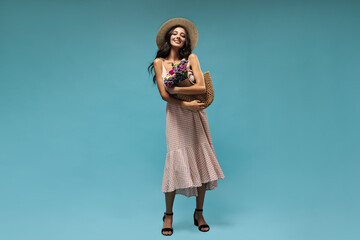 Lovely long haired woman in wide-brimmed straw hat, ping light sundress and black modern heels...