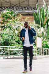 young stylish afro american male in modern station speaking on mobile phone