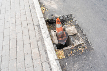 a pit on the road and a road orange cone, a concept of danger on the road