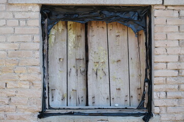 boarded up window in a brick building on a summer day