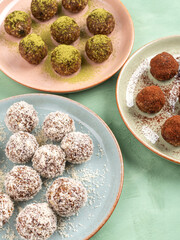 Three different taste energy balls in dishes, cocoa, coconut, matcha