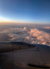 Fototapeta na wymiar Golden sunset sky with fluffy ornamental clouds, panoramic view from an airplane