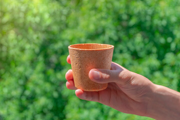 Hand holding edible waffle coffee cup on green background. Zero waste concept
