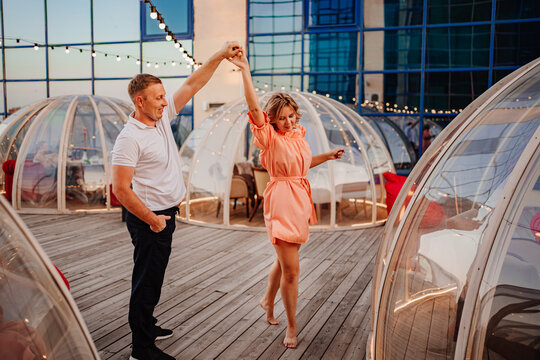a man and a woman in love dance to a rooftop cafe on a date.