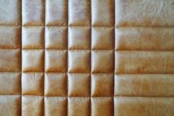Brown leather upholstery of an armchair, sofa with square and rectangular stitches of thread