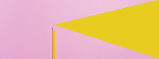 A template with copy space of a wooden yellow pencil on a pink paper background that looks minimal and clean. With a yellow triangle