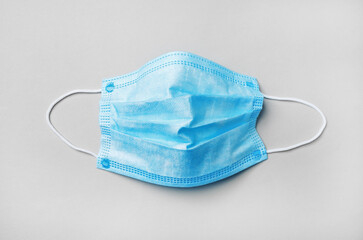 Blue medical face mask on paper background. Flat lay.