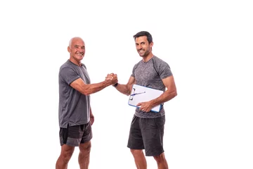 Gordijnen Fitness trainer with a workout pad shakes hands with a retired man in sports uniform. On a white isolated background. © sergojpg