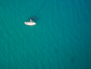 An aerial view of a sailboat with a blue ocean background.
