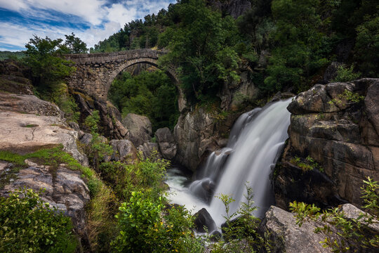 View of the ancient Mizarela Bridge or Devil&rsquo;s Bridge with a waterfall, over Rabagao river, at the Peneda Geres National Park, in Portugal, Europe