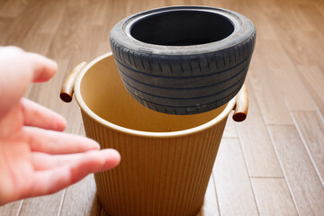 古いタイヤをゴミ箱へ投げ捨てる　
