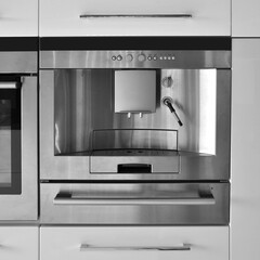 Interior of modern kitchen equipment, beige lacquer cabinets, built-in oven and coffee machine