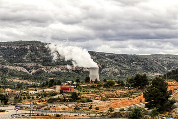 Smoking chimneys in nuclear power plant between mountains