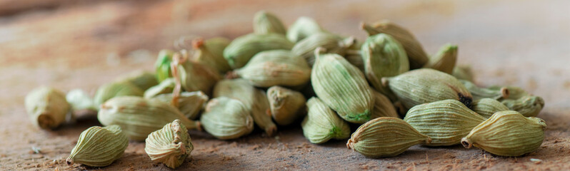 Cardamom ( Elettaria cardamomum) pods over a wooden table. Close up macro view with copy space and selective focusing. Banner photography.