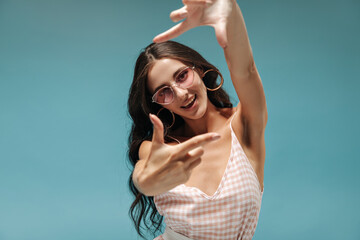 Fashionable young brunette haired lady with round earrings, pink glasses and plaid summer top...