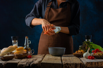 The process of preparing the dressing for the classic Caesar salad. The cook squeezes the garlic into the sauce. The products from which the Caesar salad will be prepared are on the table.