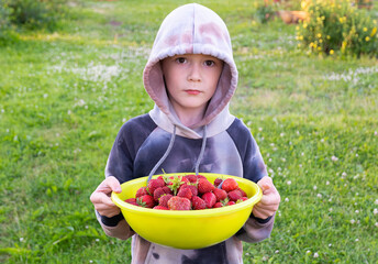 hooded boy with a large yellow bowl full of strawberries