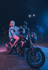 Obraz na płótnie Canvas portrait of a girl in the rays of neon light on a motorbike at night in an empty parking lot