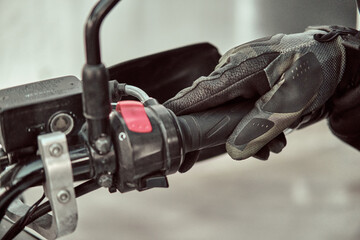 Biker holds onto the throttle handle of a motorcycle. There are kilswitch and starter buttons on...