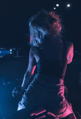 portrait of a girl in the rays of neon light on a motorbike at night in an empty parking lot