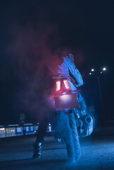 Naklejka na ściany i meble Motorcyclist makes a burnout on a motorbike in neon light, at night with clouds of tire smoke