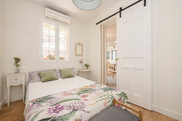 Cheerful decoration of a double bedroom with bright white tones in a vacation rental apartment.