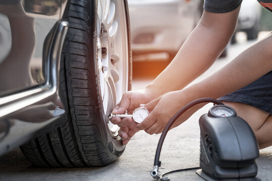 Asia man use Tire gauge analog check air pressure of wheel car on the road basic maintenance by oneself