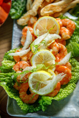 A dish of lettuce leaves, lemon and king prawns.
