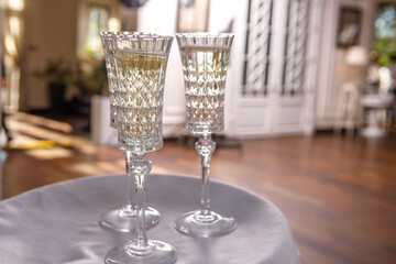 Crystal champagne glasses, illuminated by the sun, are on a tray.