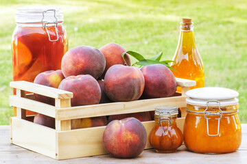 Peaches in a wood box over a table with preserve, jam, marmelade and peach liqueur