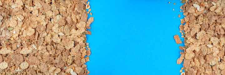 Fototapeta na wymiar Muesli. Close-up of muesli scattered on a table, breakfast cereals on a blue background. Healthy food banner with place to insert text